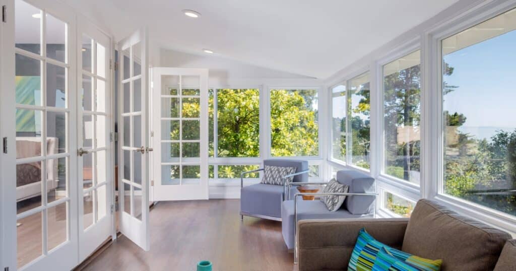 White themed sunroom with grey and brown couch