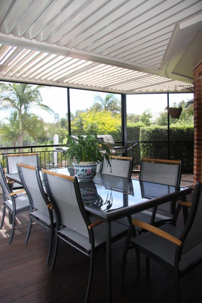 Opening roof louvres controlling sunlight over the deck and outdoor setting.