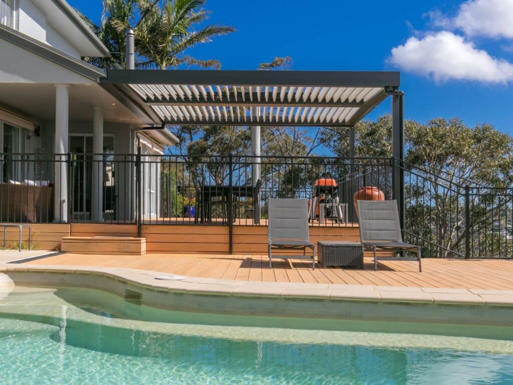 A freestanding Eclipse Opening Roof installed by the poolside with mid coast views.