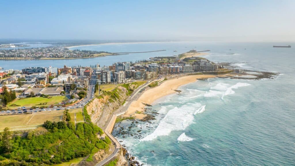 Breathtaking flyover view of Newcastle Beach and surrounding houses and apartments.