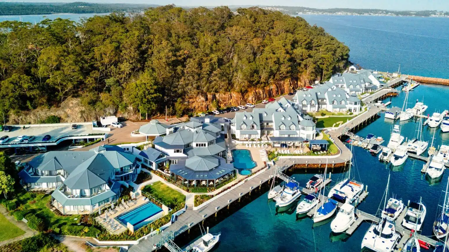 Flyover view of the Anchorage Marina in Port Stephens showing houses with balconies, verandahs, and pergolas overlooking the water.